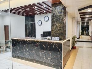 a lobby with a counter with two clocks on the wall at Hotel Al badar in Rawalpindi