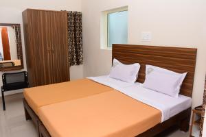 a bedroom with a large bed with a wooden headboard at Perfect Residency in Mayiladuthurai