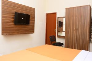 a room with a bed and a tv on a wall at Perfect Residency in Mayiladuthurai