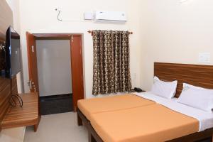 a bedroom with a bed and a television and a window at Perfect Residency in Mayiladuthurai