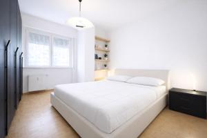 a white bedroom with a white bed and a window at Bella Vita Stays Happy in Sondrio