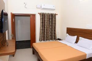 a bedroom with a bed and a television and a window at Perfect Residency in Mayiladuthurai