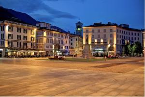 a city square with buildings and a clock tower at night at Bella Vita Stays Happy in Sondrio