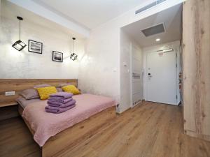 a bedroom with a bed with pink sheets and yellow pillows at Apartament KLARA in Sarbinowo +8 photos