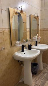 a bathroom with two sinks and two mirrors at لمسة فندقية راقية in Abū Marāgh