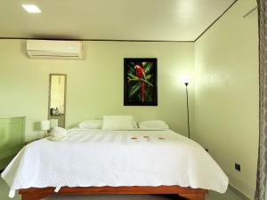 a bedroom with a white bed with a painting on the wall at Apartamentos Jireh in Quepos