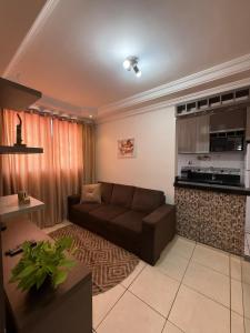 a living room with a couch and a kitchen at Apartamento próximo Aeroporto Cuiabá in Várzea Grande