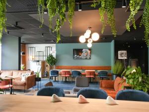 a lobby with orange and blue furniture and plants at Hôtel Ibis Vitré Centre Ville climatisé in Vitré