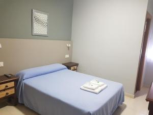 a bedroom with two beds with towels on the bed at Hostal Soto in La Virgen del Camino