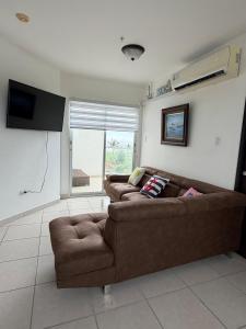 a living room with two brown couches and a television at An apartment with ocean views in Chiriquí