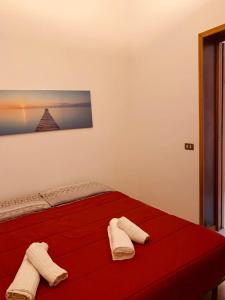 a bedroom with a red bed with two towels on it at Casa vacanze Misilla in Marsala