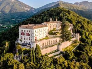 a large building on a hill with trees and mountains at Casa Maria in Valmareno