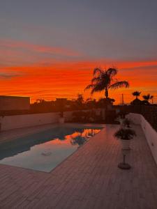 a swimming pool with a sunset in the background at Casa vacanze Misilla in Marsala