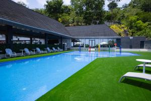 a large swimming pool with chairs and grass at Hillside hotel in Kenema