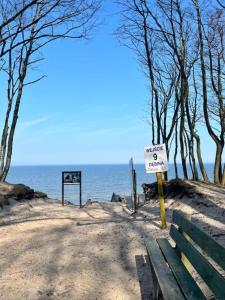 a sign on a beach with a bench and the ocean at Apartament 44A Dębina I 400 m do plażyl przyjazny rowerzystom in Debina