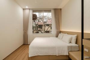 a bedroom with a white bed and a window at Residences A-25 in Hanoi