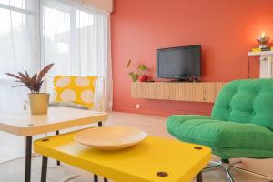 a living room with a green chair and a tv at Nid des Loriots - 3 Ch - Parking - Belle Beille Université in Angers