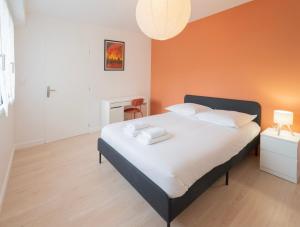 a large bed in a room with an orange wall at Nid des Loriots - 3 Ch - Parking - Belle Beille Université in Angers