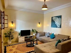 a living room with a couch and a tv at La Baïa Cozy in Sukrah