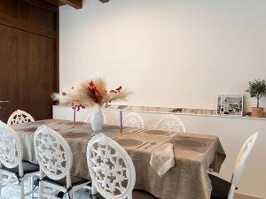 a dining room table with white chairs and a vase with flowers at DaVilla Sanremo - Entire Villa, Sea View & Pool in Pampara