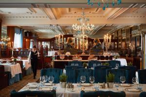 a dining room with tables with blue chairs and a waiter at Rubens At The Palace in London