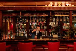 a man sitting at a bar with a drink at Rubens At The Palace in London