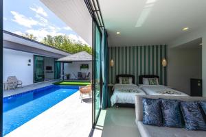 a bedroom with two beds and a swimming pool at Lespalm Resort by Vacayandco in Ban Thalat Choeng Thale
