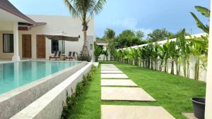 a swimming pool next to a villa with a palm tree at Lespalm Resort by Vacayandco in Ban Thalat Choeng Thale +23 photos