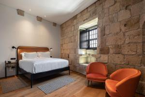 a bedroom with a bed and a brick wall at Exmo Hotel by Olivia in Porto