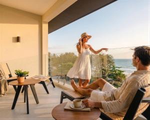 a man and woman sitting in chairs in front of a window at Iguana Surf Boutique Hotel Tamarindo Rooftop Pool & Beachfront Suites in Tamarindo
