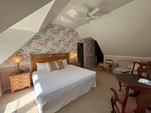 a bedroom with a bed and a table and a chair at Auberge Le Tricorne in North Hatley