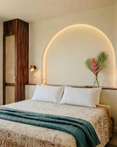 a bedroom with a bed with a vase of flowers on it at Iguana Surf Boutique Hotel Tamarindo Rooftop Pool & Beachfront Suites in Tamarindo