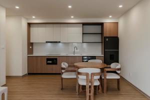 a kitchen with a wooden table and white cabinets at Residences A-25 in Hanoi