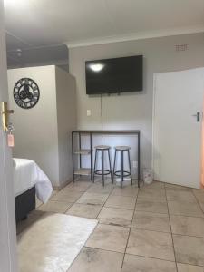 a room with two bar stools and a tv on the wall at La Bushka Guesthouse in Bela-Bela