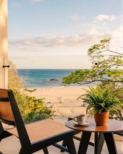 a table and a chair on a balcony with a beach at Iguana Surf Boutique Hotel Tamarindo Rooftop Pool & Beachfront Suites in Tamarindo