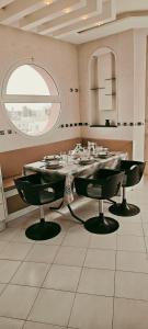 a dining room with a table and chairs and a window at Dar Essaada - Exceptionel duplex de 270 M2, plage à 2 min à pieds in Mahdia