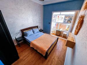 a bedroom with a bed with blue walls and a window at Itrane Hostel in Tamraght Ouzdar