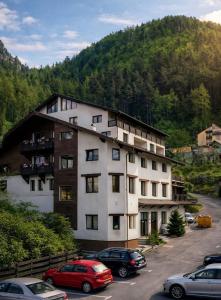 a large building with cars parked in a parking lot at Classic Inn Hotel in Braşov
