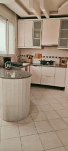 a large kitchen with white cabinets and a counter top at Dar Essaada - Exceptionel duplex de 270 M2, plage à 2 min à pieds in Mahdia +57 photos