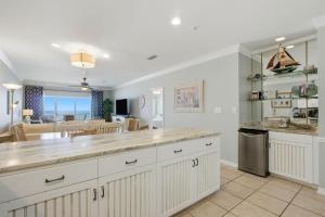 a kitchen with white cabinets and a living room at Marlin Key 2D in Orange Beach