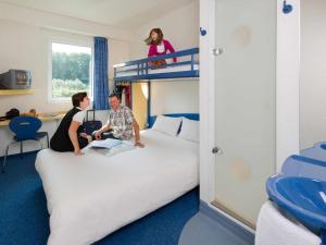two people sitting on top of a bed in a room at ibis budget Aachen Raeren Grenze in Raeren