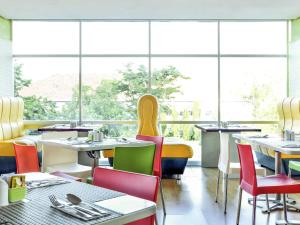 a restaurant with tables and chairs and large windows at ibis Semarang Simpang Lima in Semarang