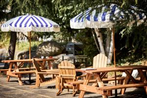 a group of wooden tables and chairs with umbrellas at Motel Boutique Hygge - anciennement Aux Portes du Soleil in Baie-Saint-Paul