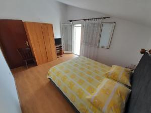 a bedroom with a bed with a yellow comforter at Apartmani Mare Palada in Marina