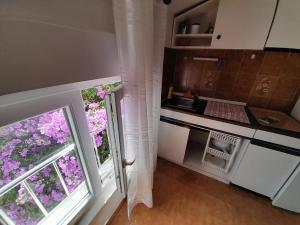 a kitchen with a sink and a window with purple flowers at Apartmani Mare Palada in Marina +10 photos