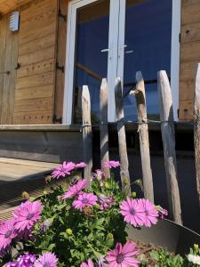 a fence with pink flowers in front of a house at Le colibri des prés in Maurens