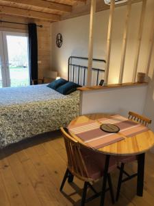 a bedroom with a bed and a table and a table and chair at Le colibri des prés in Maurens