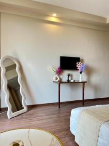 a living room with a tv and a table with flowers at Veloria Grand Suites in Greater Noida