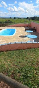 a swimming pool with tables and benches in a yard at Pousada Xodó in São Pedro