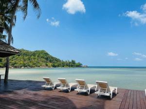 a row of white chairs sitting on a beach at Nirvana By the Sea in Ban Madua Wan